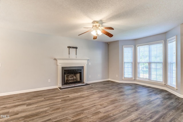 unfurnished living room featuring dark wood-type flooring, a textured ceiling, and ceiling fan