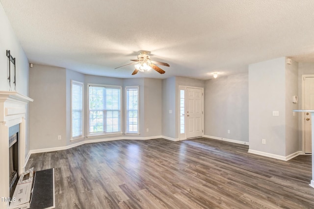 unfurnished living room with ceiling fan, dark wood-type flooring, and a textured ceiling