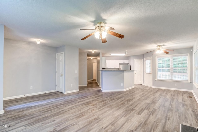 unfurnished living room with a textured ceiling, ceiling fan, and light hardwood / wood-style floors