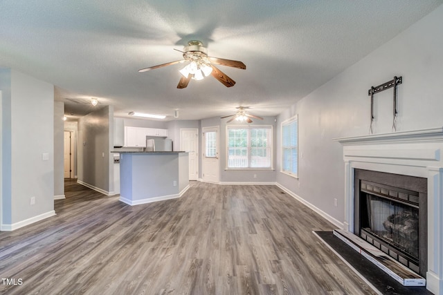 unfurnished living room with hardwood / wood-style floors, a textured ceiling, and ceiling fan