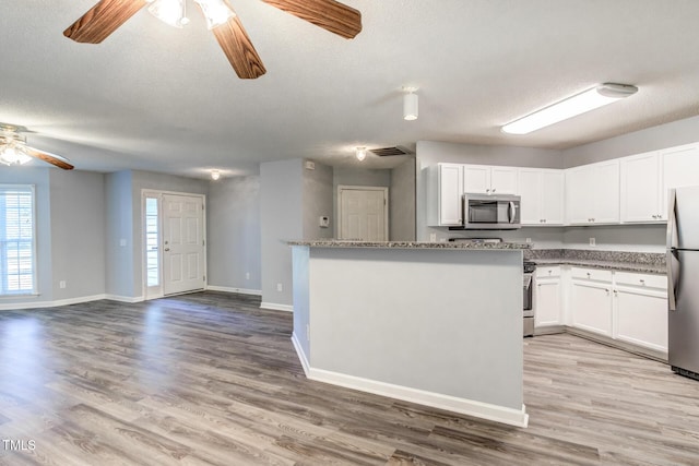 kitchen featuring stone counters, stainless steel appliances, light hardwood / wood-style floors, and white cabinets