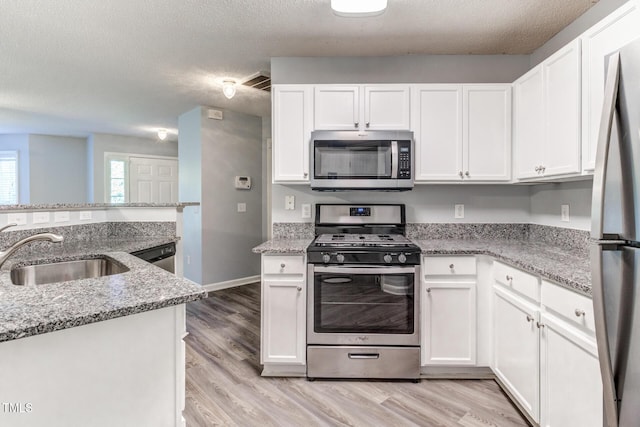 kitchen featuring white cabinetry, appliances with stainless steel finishes, sink, and light stone counters