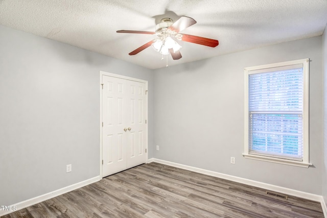 spare room featuring hardwood / wood-style floors, a wealth of natural light, a textured ceiling, and ceiling fan