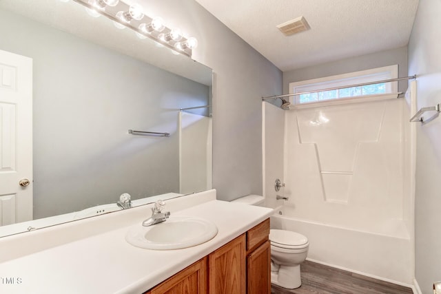 full bathroom with  shower combination, hardwood / wood-style floors, vanity, a textured ceiling, and toilet