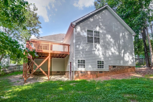 back of property with a wooden deck and a lawn