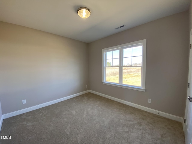 empty room featuring carpet floors, baseboards, and visible vents