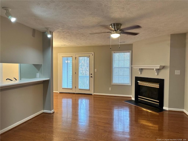 unfurnished living room with dark wood-type flooring, ceiling fan, and a textured ceiling