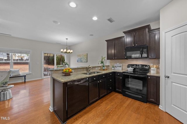 kitchen with sink, decorative light fixtures, kitchen peninsula, light hardwood / wood-style floors, and black appliances