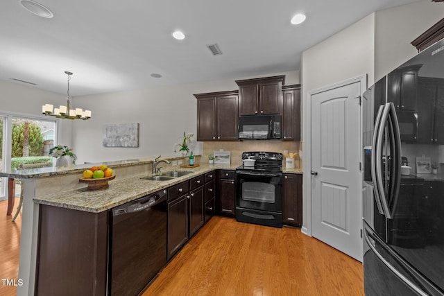 kitchen featuring decorative light fixtures, black appliances, sink, light hardwood / wood-style floors, and kitchen peninsula