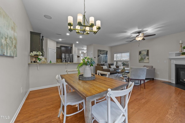 dining room with ceiling fan with notable chandelier and light hardwood / wood-style flooring