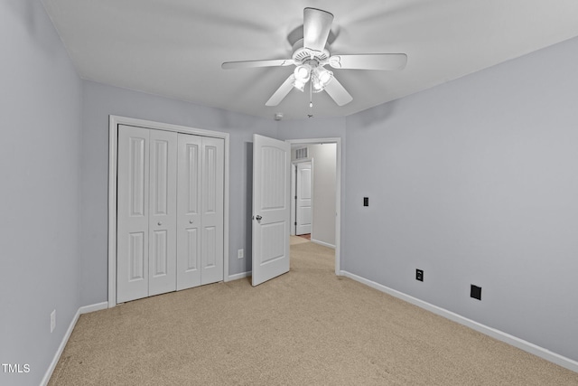 unfurnished bedroom featuring ceiling fan, a closet, and light carpet