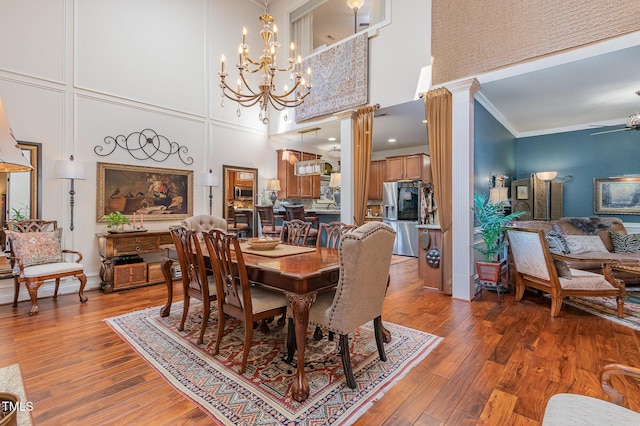 dining area featuring ornate columns, ceiling fan, crown molding, and wood finished floors