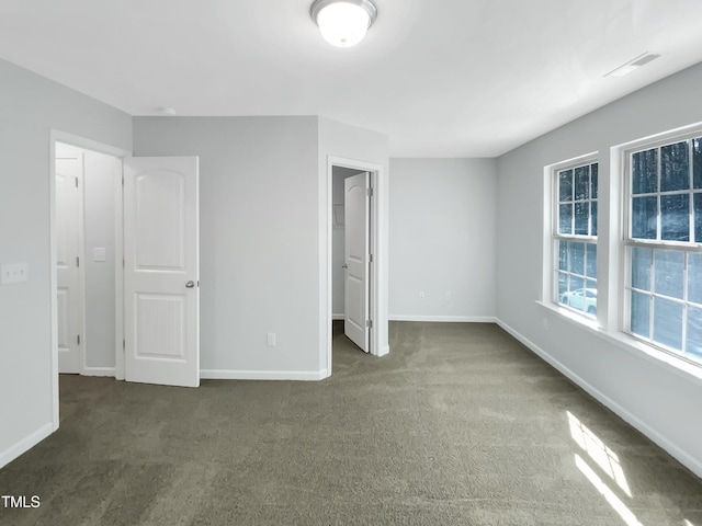 interior space with dark colored carpet, a walk in closet, and a closet