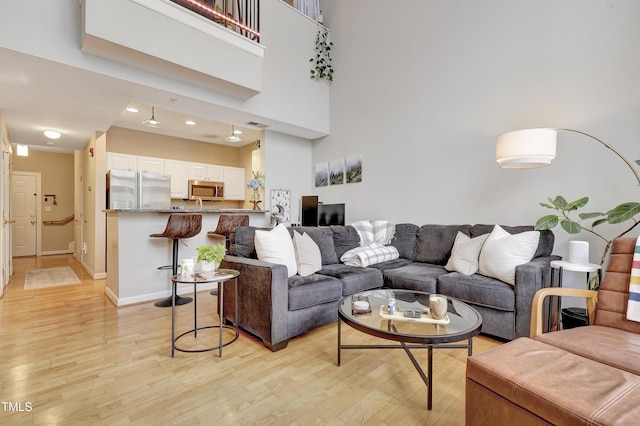 living room featuring a towering ceiling and light hardwood / wood-style floors