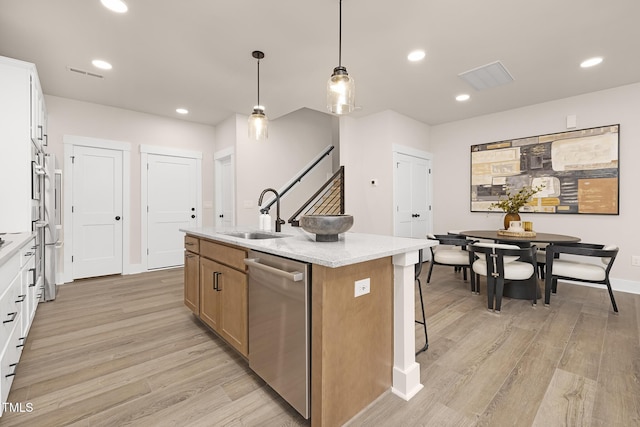 kitchen featuring dishwasher, sink, white cabinets, and an island with sink