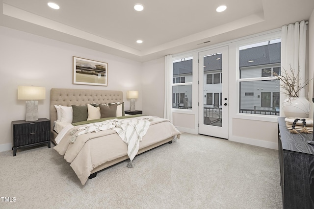 carpeted bedroom with a raised ceiling and access to outside