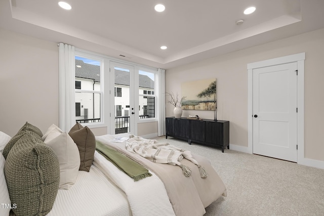 carpeted bedroom featuring access to exterior, a raised ceiling, and french doors