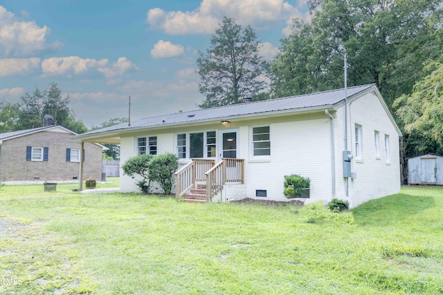 rear view of property with a storage shed and a lawn