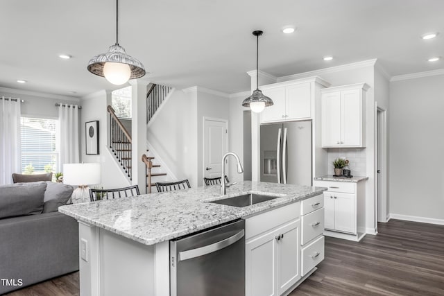 kitchen with sink, white cabinetry, decorative light fixtures, appliances with stainless steel finishes, and a kitchen island with sink