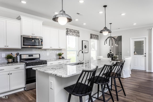 kitchen featuring white cabinetry, sink, stainless steel appliances, and an island with sink