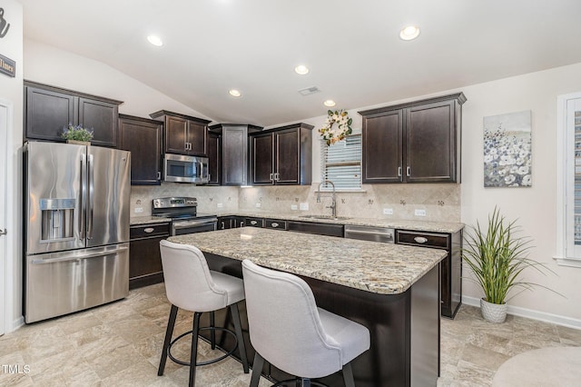 kitchen with lofted ceiling, a breakfast bar area, stainless steel appliances, dark brown cabinets, and a sink