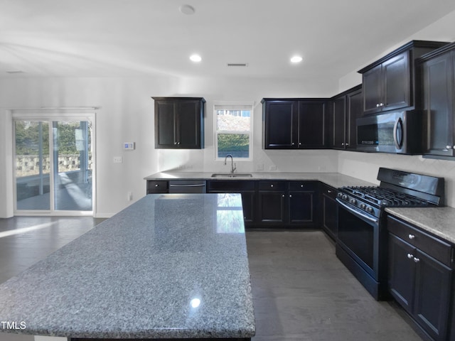 kitchen with stainless steel appliances, light stone countertops, and sink