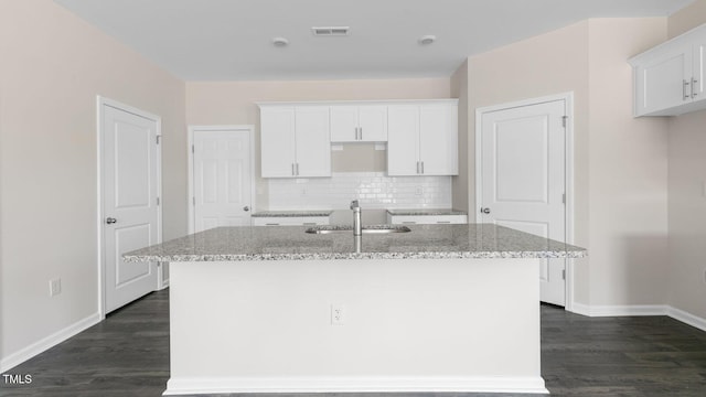 kitchen featuring a kitchen island with sink, sink, and light stone countertops