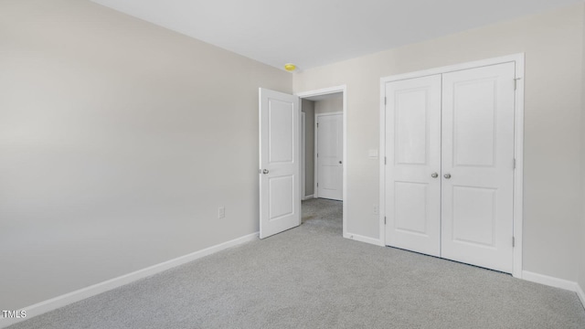 unfurnished bedroom with light colored carpet and a closet