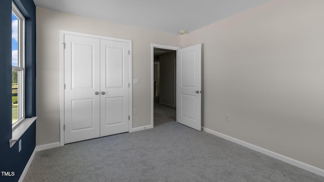 unfurnished bedroom with light colored carpet and a closet