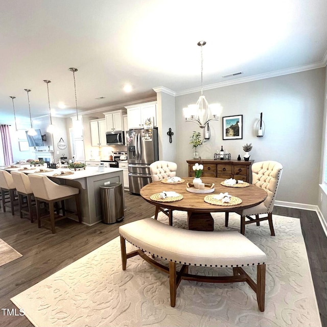 dining area featuring dark wood-type flooring, ornamental molding, and a chandelier