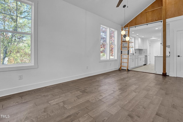 unfurnished dining area featuring vaulted ceiling, sink, ceiling fan, and light hardwood / wood-style flooring