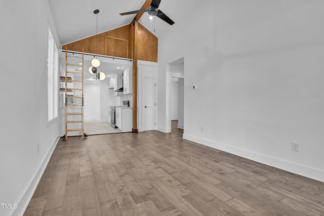 unfurnished living room featuring high vaulted ceiling, beam ceiling, light hardwood / wood-style floors, and ceiling fan