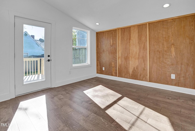 interior space featuring lofted ceiling, dark hardwood / wood-style floors, and wood walls