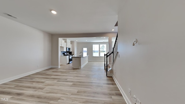 corridor with sink and light hardwood / wood-style flooring