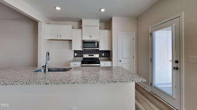 kitchen with white cabinetry, sink, decorative backsplash, light stone counters, and stainless steel appliances