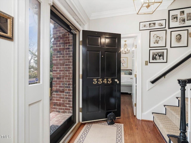 entrance foyer featuring ornamental molding, a chandelier, and wood-type flooring