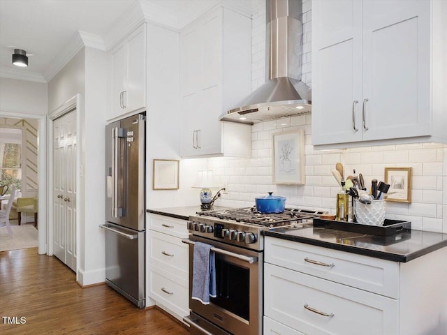 kitchen featuring white cabinetry, high end appliances, and wall chimney exhaust hood