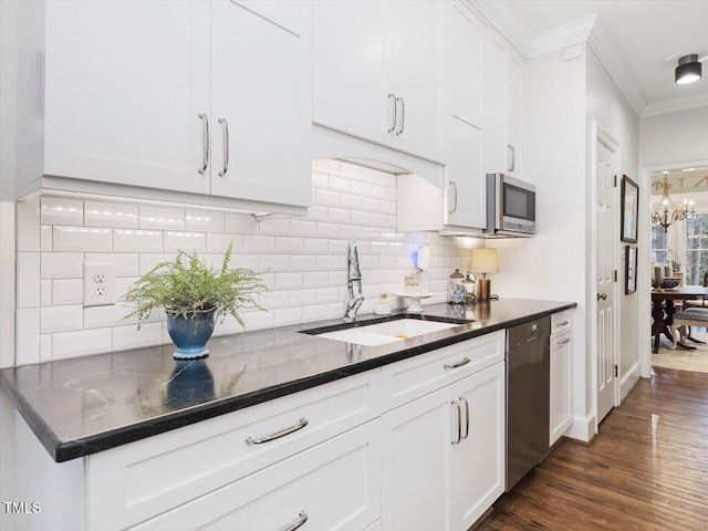 kitchen with appliances with stainless steel finishes, sink, white cabinets, dark hardwood / wood-style flooring, and ornamental molding