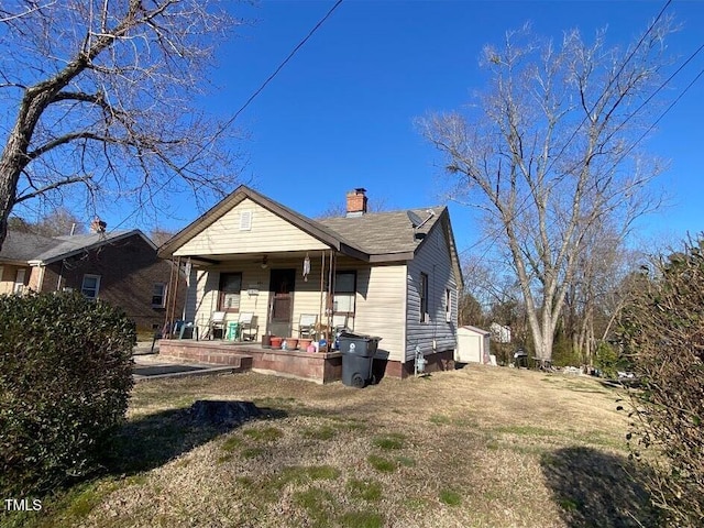 back of property with covered porch and a chimney