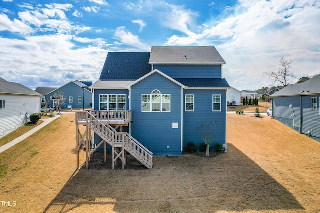 back of property with roof with shingles, stairway, and a wooden deck