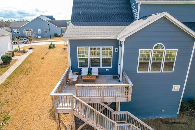 back of property with a wooden deck, stairs, and roof with shingles