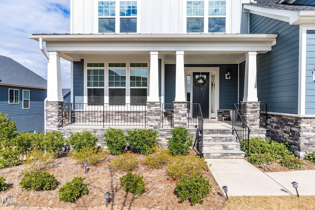 property entrance with covered porch, stone siding, and board and batten siding