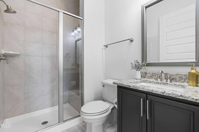 bathroom with a stall shower, vanity, and toilet