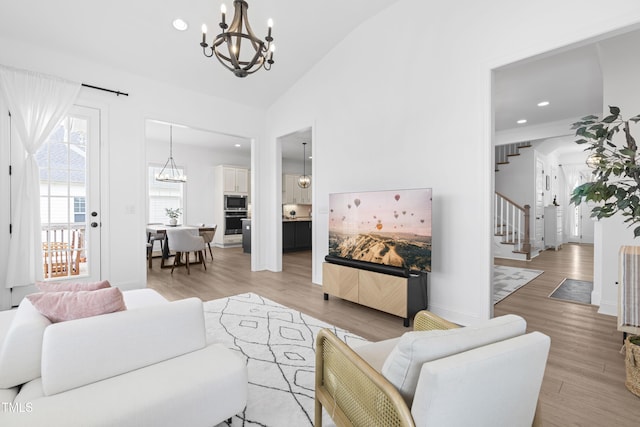 living area featuring recessed lighting, light wood-style floors, stairs, vaulted ceiling, and an inviting chandelier