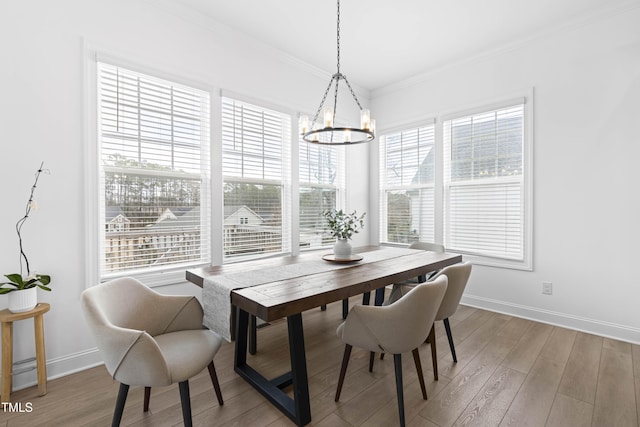 dining area with light wood-type flooring, baseboards, and crown molding