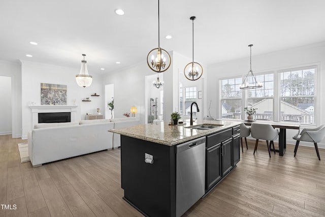 kitchen with a fireplace, light wood finished floors, a sink, dark cabinets, and dishwasher