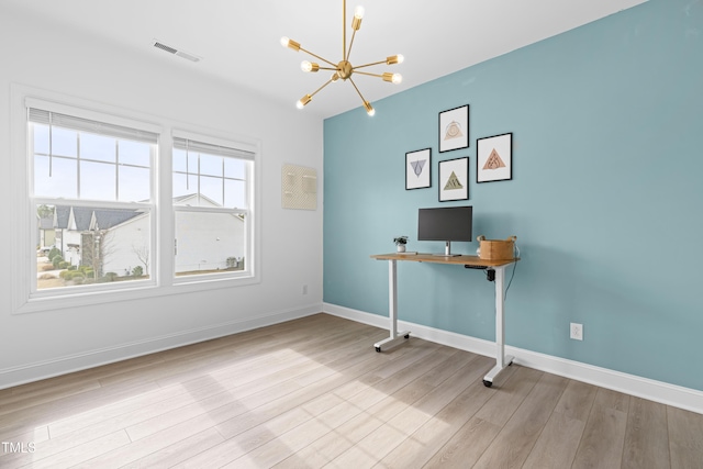 unfurnished office featuring baseboards, wood finished floors, visible vents, and a notable chandelier