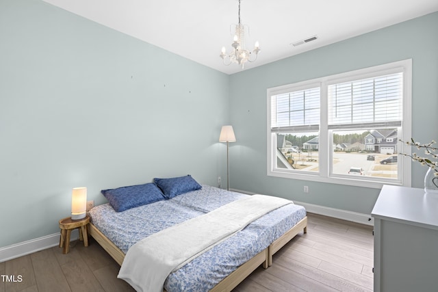 bedroom featuring visible vents, baseboards, and wood finished floors