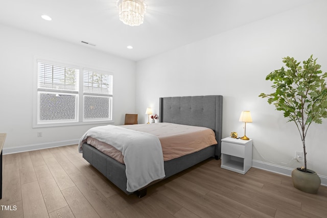 bedroom with wood finished floors, visible vents, and baseboards