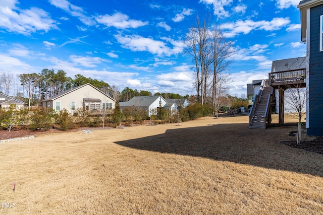 view of yard with a residential view, stairs, and a wooden deck